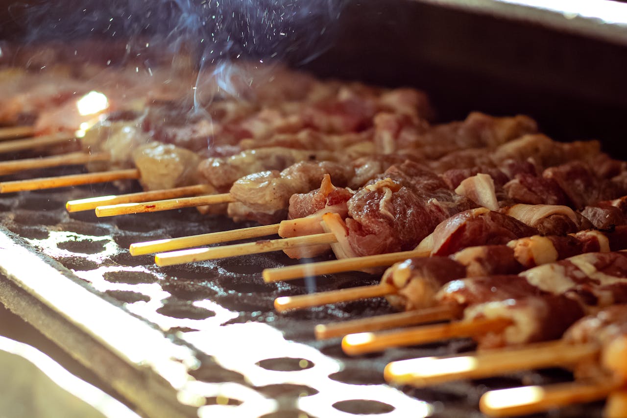 About Delicious meat skewers grilling on an open barbecue with smoke rising.